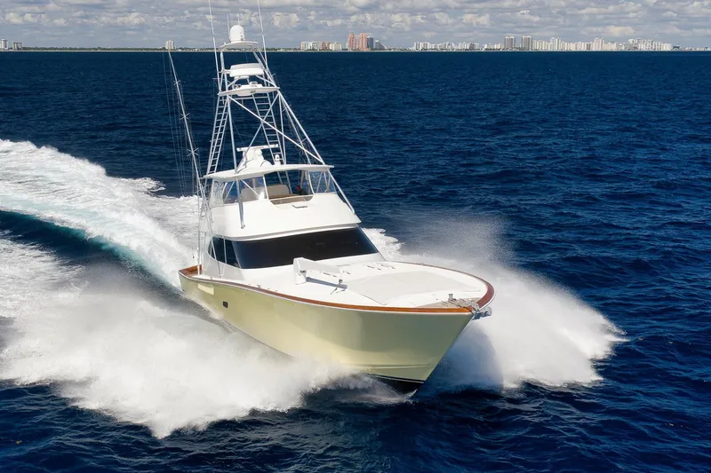 Slide: The Image of 2010 Viking 82 Convertible yacht cruising on open ocean with city skyline in background. - 2