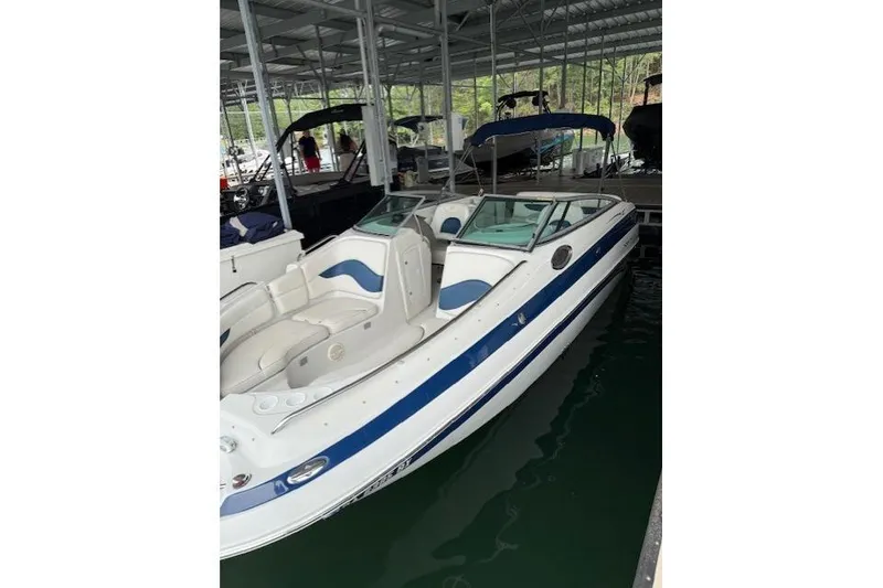 Slide: The Image of 2003 Crownline 239 DB boat docked in a marina, featuring white and blue design. - 5