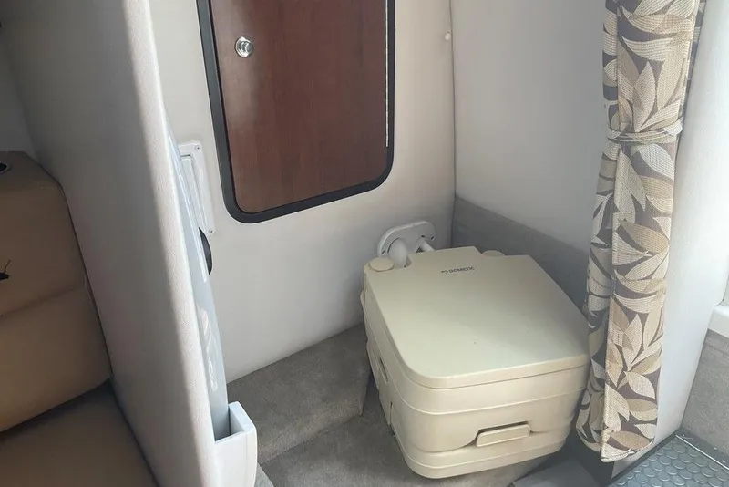 Slide: The Image of 2015 Crownline 236 SC cabin interior with portable toilet and floral curtain. - 19