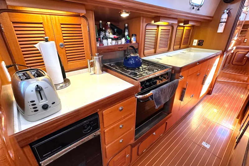 Slide: The Image of Luxurious 2006 Passport 470 yacht kitchen with wooden cabinetry, stove, and modern appliances. - 13