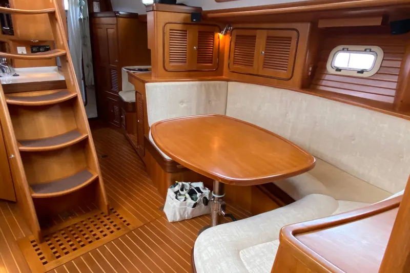 Slide: The Image of Luxurious 2006 Passport 470 yacht interior with wooden dining area and staircase. - 2