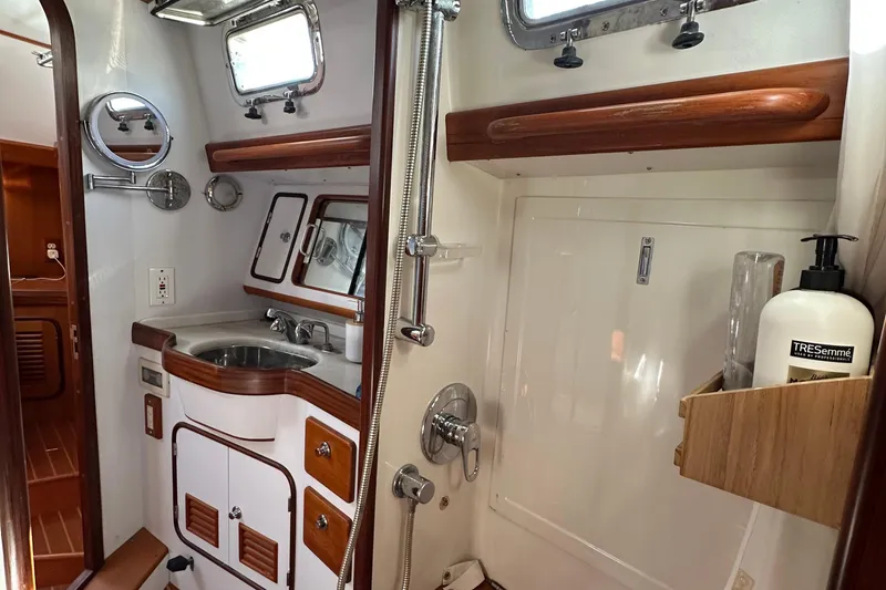 Slide: The Image of Compact bathroom in a 2006 Passport 470 yacht, featuring a sink, shower, and wooden accents. - 31