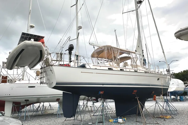 Slide: The Image of 2006 Passport 470 sailboat on stands in a boatyard, under cloudy skies. - 4