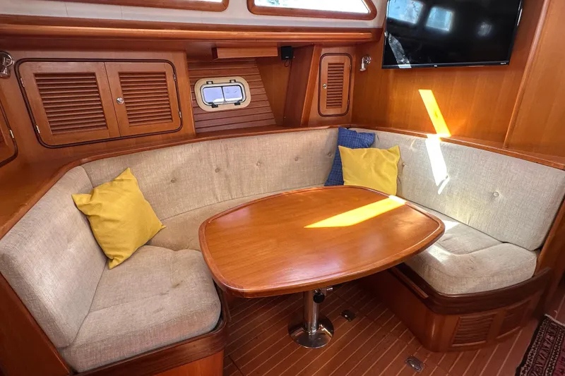 Slide: The Image of Cozy interior of 2006 Passport 470 yacht with cushioned seating and wooden table. - 6