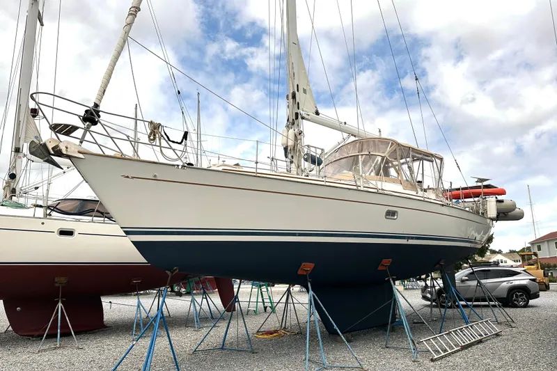 Slide: The Image of Sailboat on stands, Passport 470 model, 2006, in a boatyard with cloudy sky. - 69