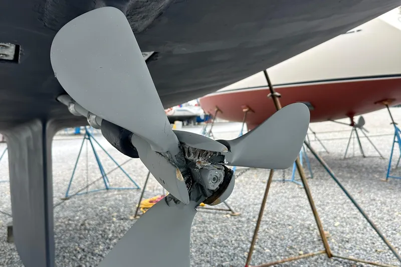 Slide: The Image of Damaged propeller of a 2006 Passport 470 sailboat on a gravel boatyard. - 70