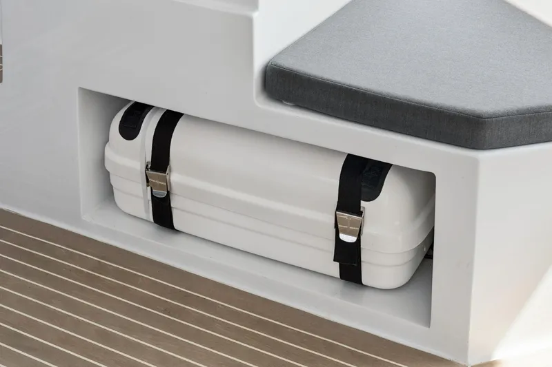 Slide: The Image of 2024 St Francis 460 boat storage compartment with secured white case and cushioned seating. - 116