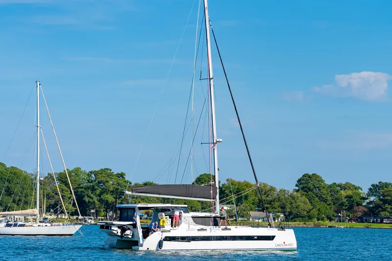 Slide: The Image of 2024 St Francis 460 catamaran sailing on a sunny day with lush greenery in the background. - 171