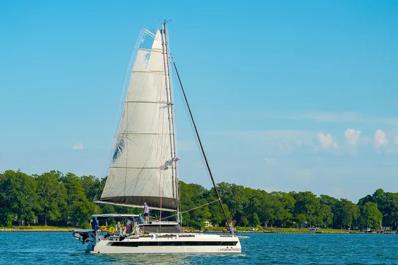 Slide: The Image of 2024 St Francis 460 sailboat cruising on a serene lake with lush green shoreline. - 173