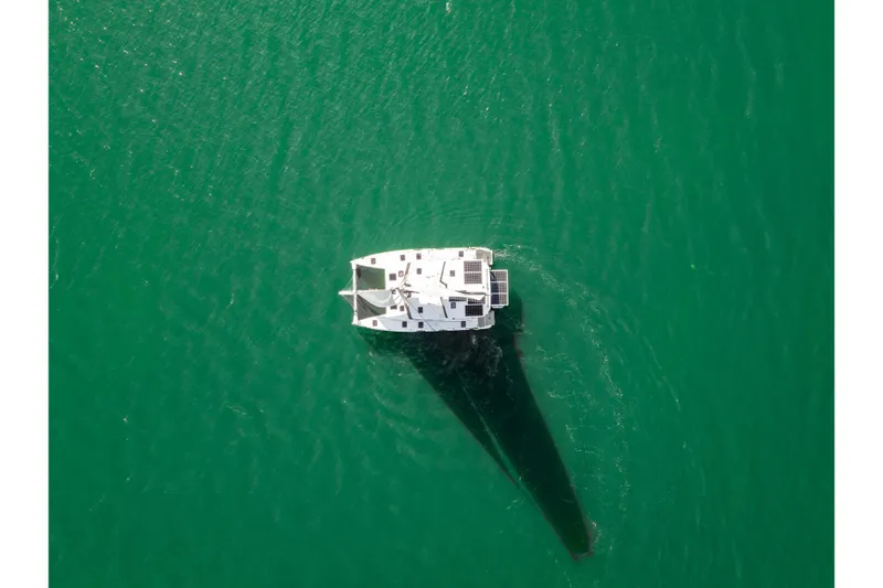 Slide: The Image of Aerial view of 2024 St Francis 460 catamaran sailing on clear green water. - 174