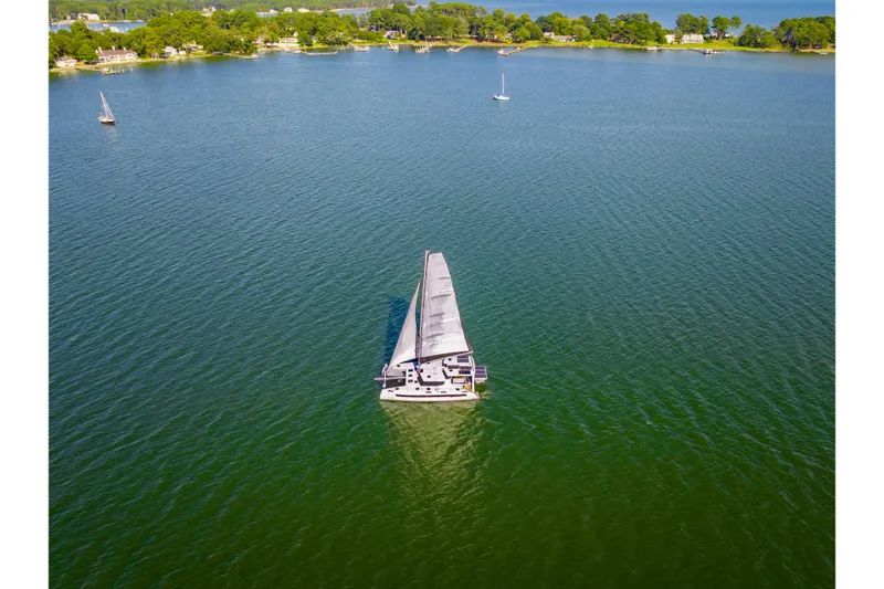 Slide: The Image of Sailboat St Francis 460, 2024 model, cruising on a serene lake with lush green surroundings. - 175