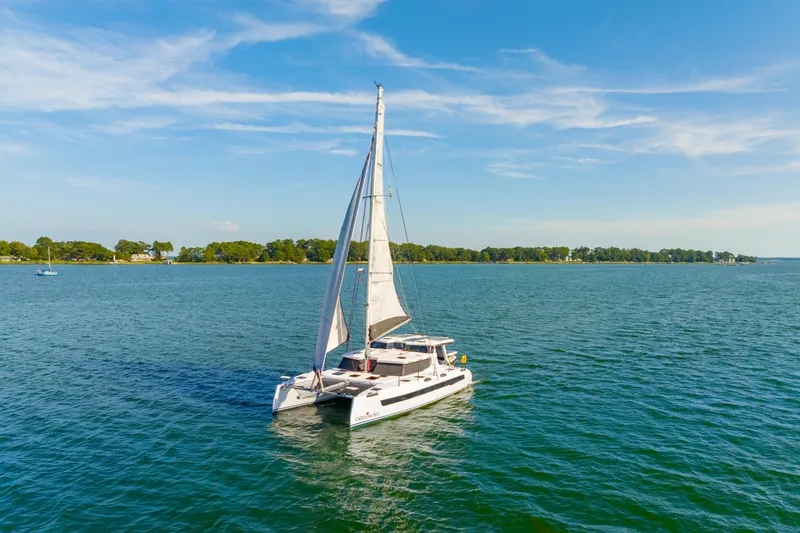 The Image of 2024 St Francis 460 catamaran sailing on a serene blue lake under a clear sky. - 2