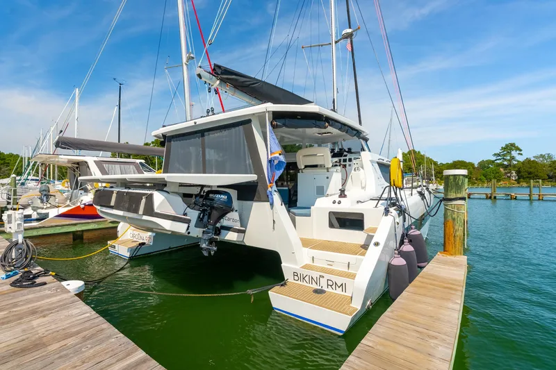 Slide: The Image of 2024 St Francis 460 catamaran docked at marina, featuring modern design and outboard motor. - 6