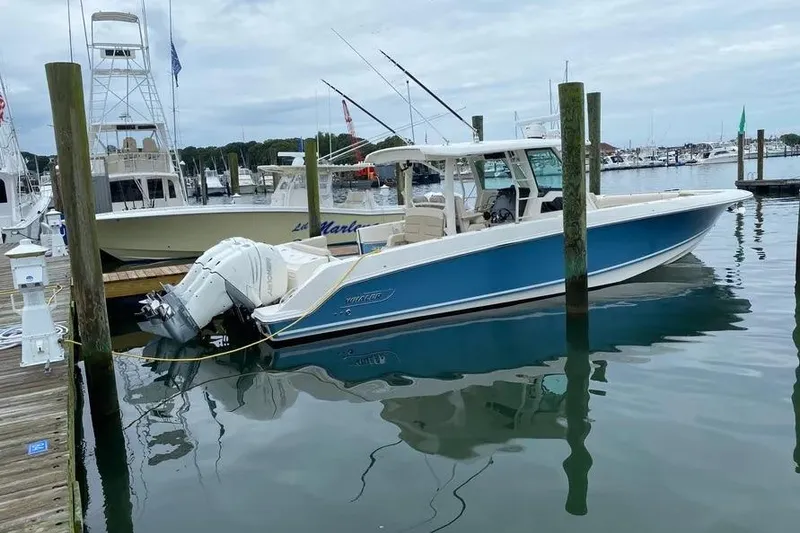 The Image of 2019 Boston Whaler 380 Outrage docked at marina, featuring sleek blue hull design. - 1