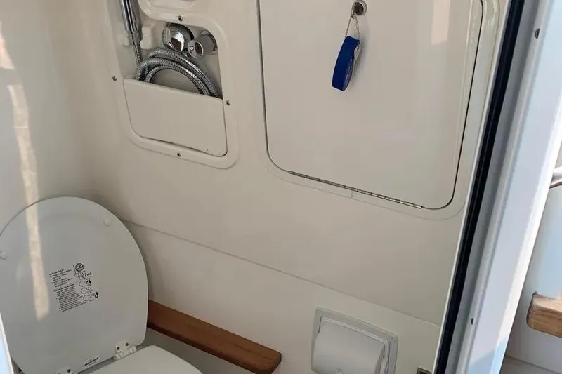 Slide: The Image of 2019 Boston Whaler 380 Outrage boat bathroom interior with toilet and storage compartment. - 25