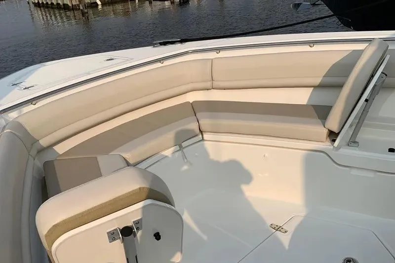 Slide: The Image of 2019 Boston Whaler 380 Outrage boat interior with cushioned seating, dockside view. - 9