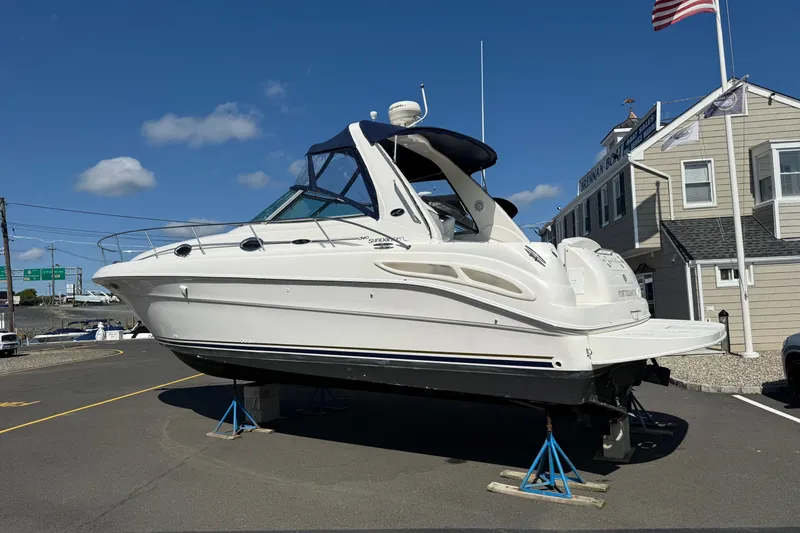 Slide: The Image of 2002 Sea Ray 340 Sundancer boat on stands, displayed outdoors under a clear blue sky. - 10
