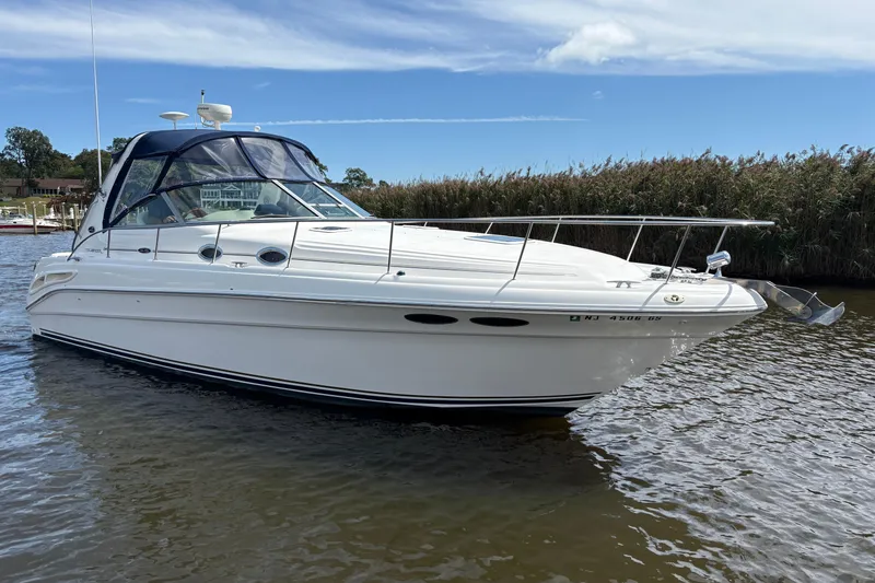 Slide: The Image of 2002 Sea Ray 340 Sundancer boat on calm water under a blue sky. - 2