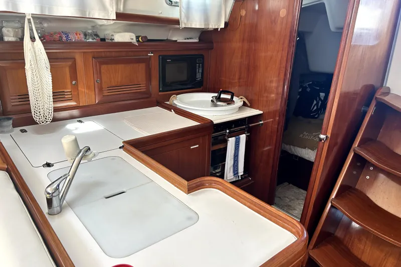 Slide: The Image of Interior of 2003 Beneteau Oceanis Clipper 473 yacht, featuring a compact kitchen area. - 14