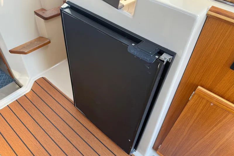 Slide: The Image of 2017 Ranger Tugs R-23 interior with wooden flooring and compact refrigerator. - 17
