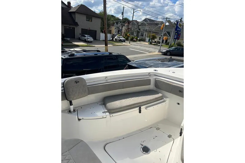 Slide: The Image of 2022 Sea Pro 239 Sport boat interior with cushioned seating, parked in a residential area. - 8