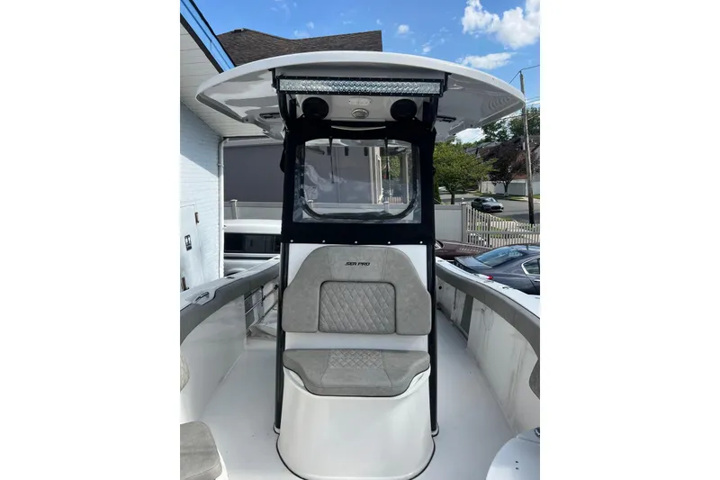 Slide: The Image of 2022 Sea Pro 239 Sport boat with cushioned seating and T-top under a clear sky. - 6