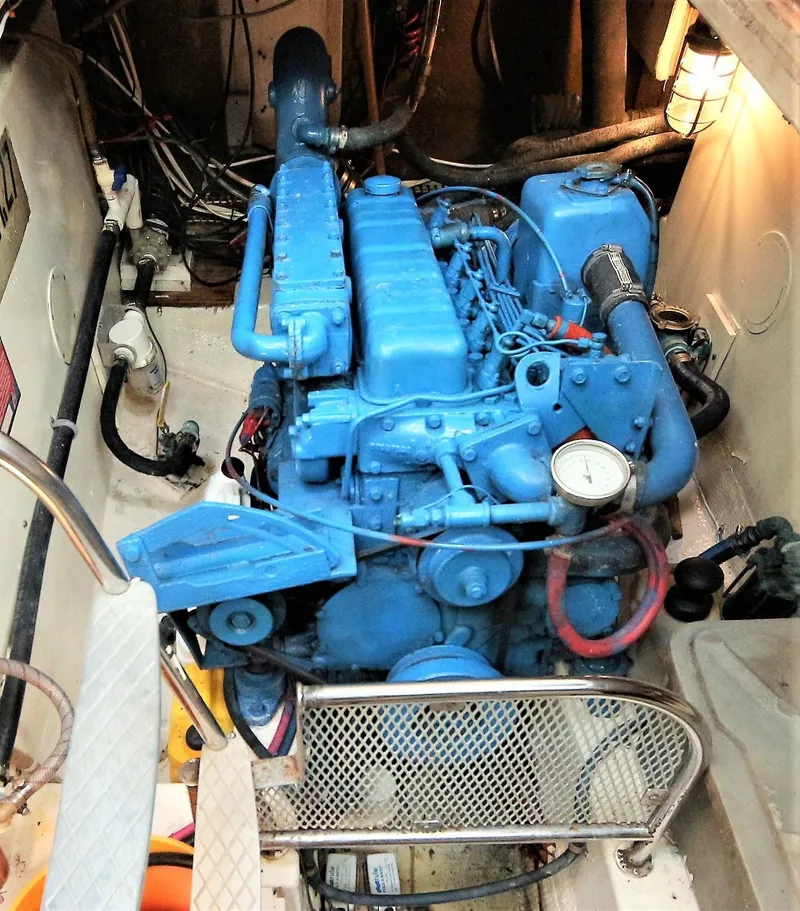 Slide: The Image of 1980 Gulfstar 47 Sailmaster cockpit with blue cushions and wooden steering wheel, docked at marina. - 18