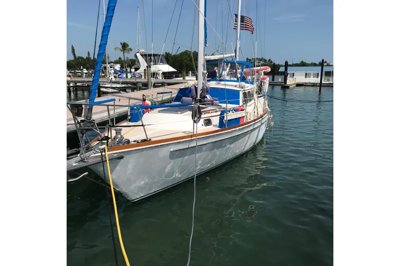 The Image of 1980 Gulfstar 47 Sailmaster docked at marina, featuring blue and white sails. - 0