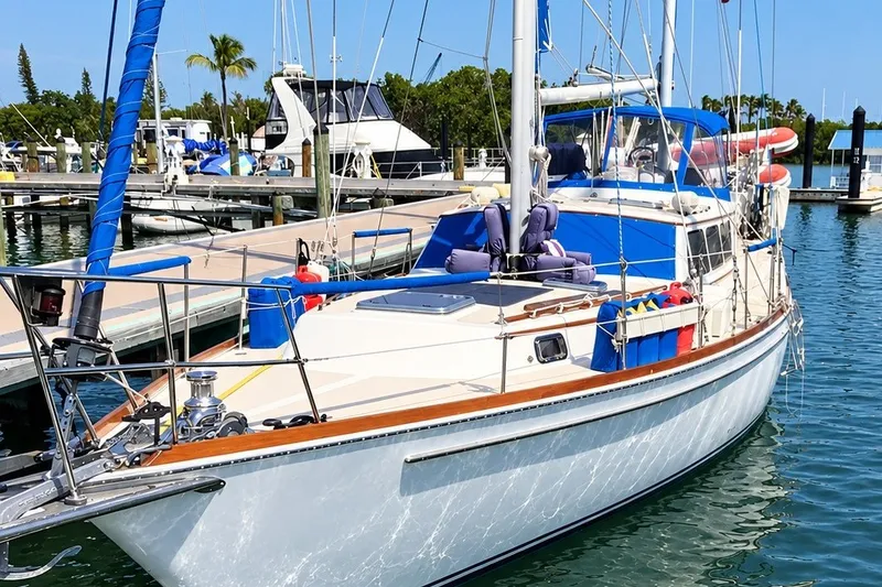 The Image of 1980 Gulfstar 47 Sailmaster docked at marina, featuring blue accents and spacious deck. - 0