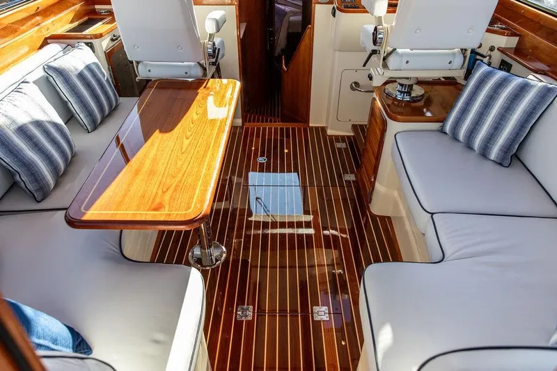 Slide: The Image of 2005 Hinckley Talaria 44 yacht interior with wooden finishes and white seating at a marina. - 12