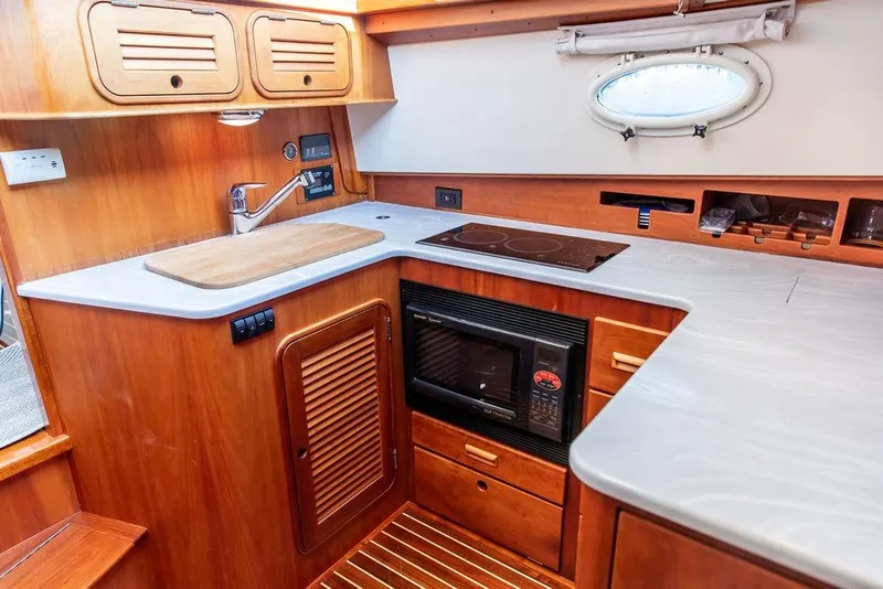Slide: The Image of 2005 Hinckley Talaria 44 yacht kitchen with stove, microwave, and wooden cabinetry. - 23