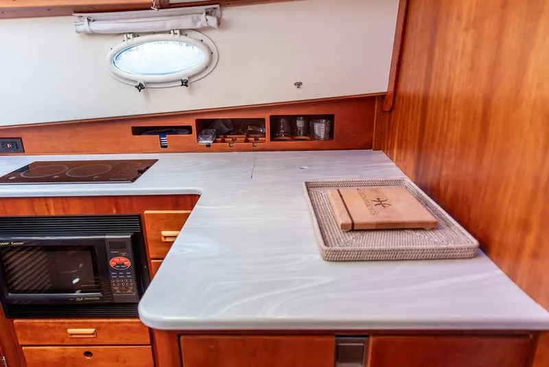 Slide: The Image of 2005 Hinckley Talaria 44 yacht interior with wooden cabinetry and modern kitchen amenities. - 24
