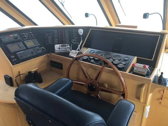 Slide: The Image of Pilothouse interior of 1989 Custom Aluminum J Simpson, featuring navigation controls and wooden steering wheel. - 27