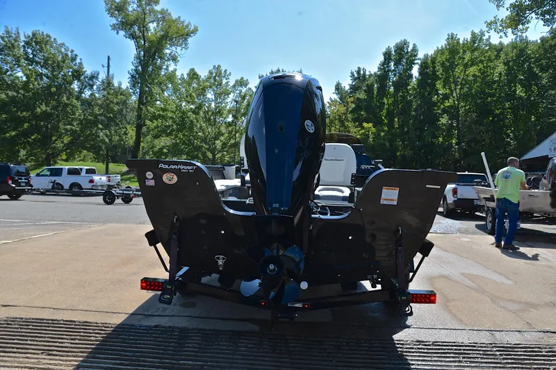 Slide: The Image of 2024 Polar Kraft 165 boat on trailer, rear view, in a parking area with trees. - 13