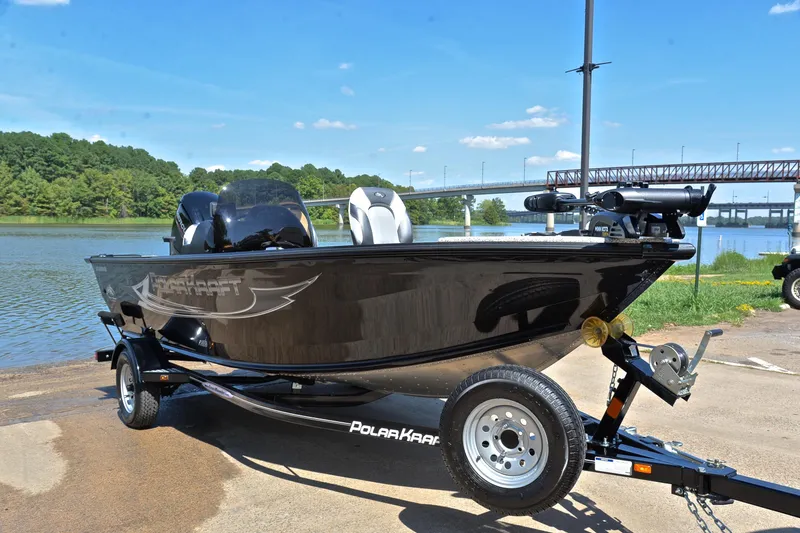 Slide: The Image of 2024 Polar Kraft 165 boat on trailer by a scenic lake with bridge in background. - 16