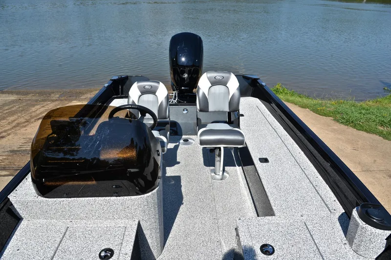 Slide: The Image of 2024 Polar Kraft 165 boat interior with seating and steering, docked by a lake. - 20