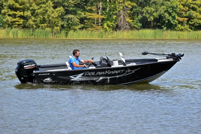 Slide: The Image of 2024 Polar Kraft 165 boat cruising on a serene lake with lush green background. - 7