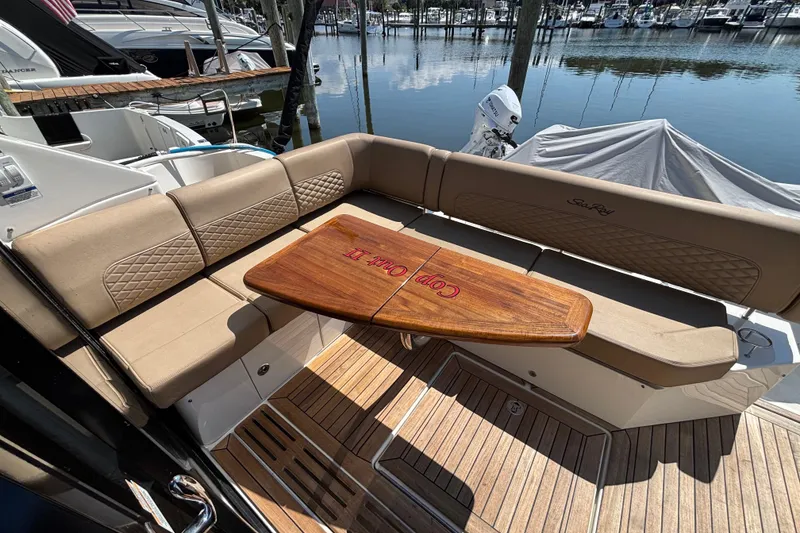 Slide: The Image of 2018 Sea Ray Sundancer 460 yacht with elegant seating and wooden table at marina. - 5