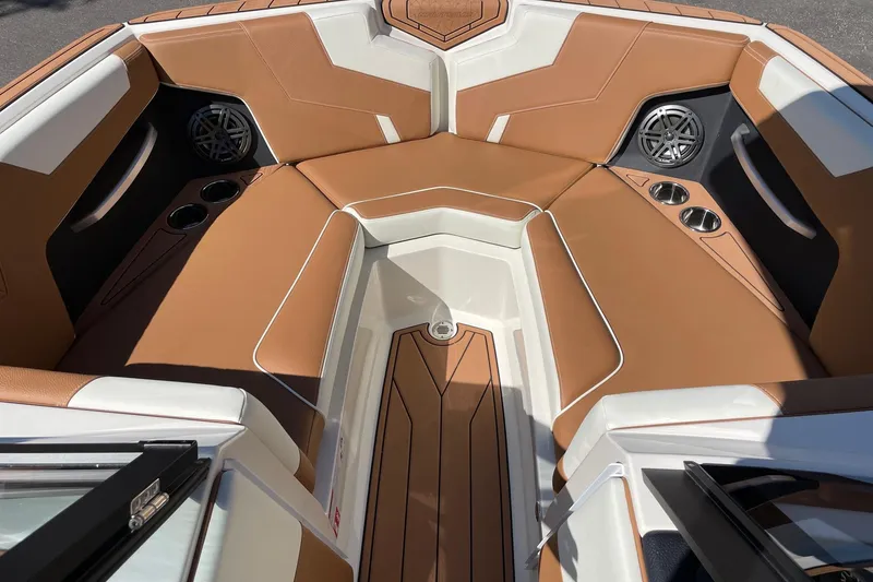Slide: The Image of 2026 Nautique Super Air Nautique GS22 boat interior with tan and white seating, cup holders, and speakers. - 11