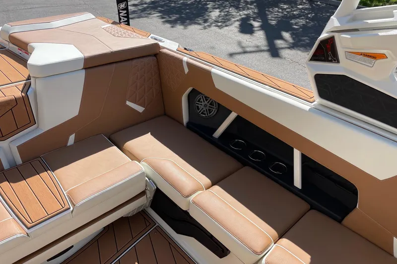 Slide: The Image of 2026 Nautique Super Air Nautique GS22 interior with tan and white seating, cup holders, and speaker. - 9