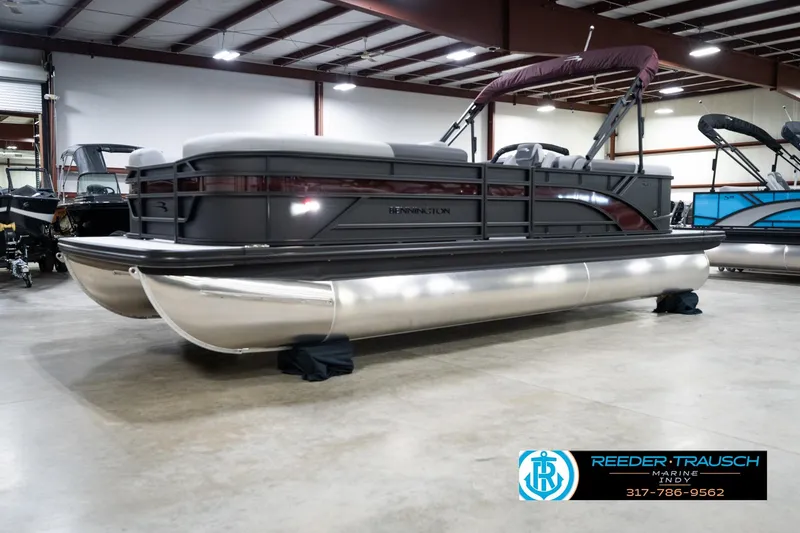Slide: The Image of 2026 Bennington 23 SSR pontoon boat displayed indoors at Reeder-Trausch Marine showroom. - 2
