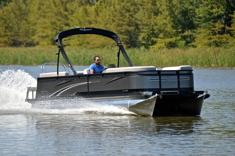 The Image of 2023 Qwest LT 822 pontoon boat cruising on a serene lake with lush greenery. - 1