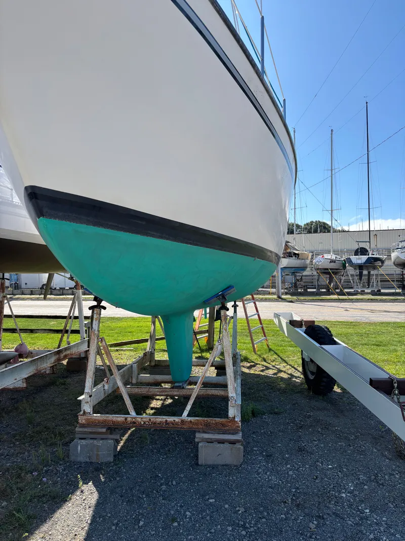 Slide: The Image of 1982 S2 8.5 sailboat on stands, hull painted turquoise, in a boatyard. - 10