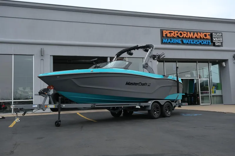 The Image of 2026 MasterCraft XT23 boat on trailer outside marine dealership. - 1