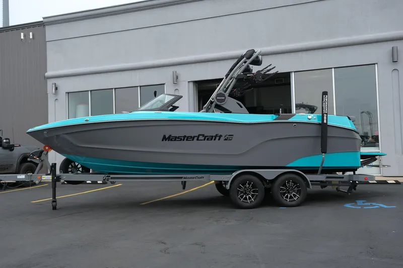 Slide: The Image of 2026 MasterCraft XT23 boat on trailer, parked outside a building. - 2