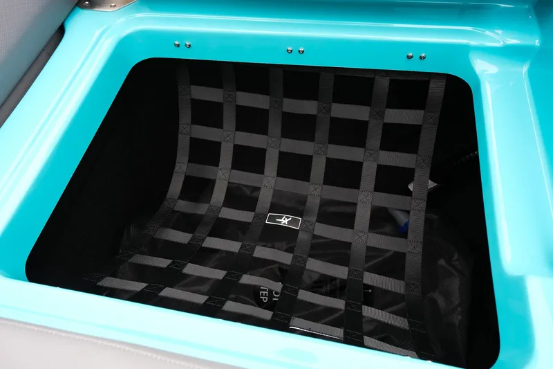 Slide: The Image of 2026 MasterCraft XT23 storage compartment with black netting and turquoise trim. - 33