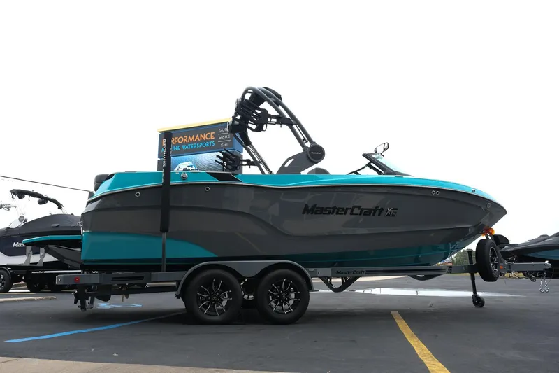 Slide: The Image of 2026 MasterCraft XT23 boat on trailer, teal and gray design, parked outdoors. - 35