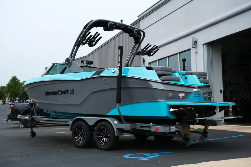 Slide: The Image of 2026 MasterCraft XT23 boat on trailer, parked outside a building. - 4