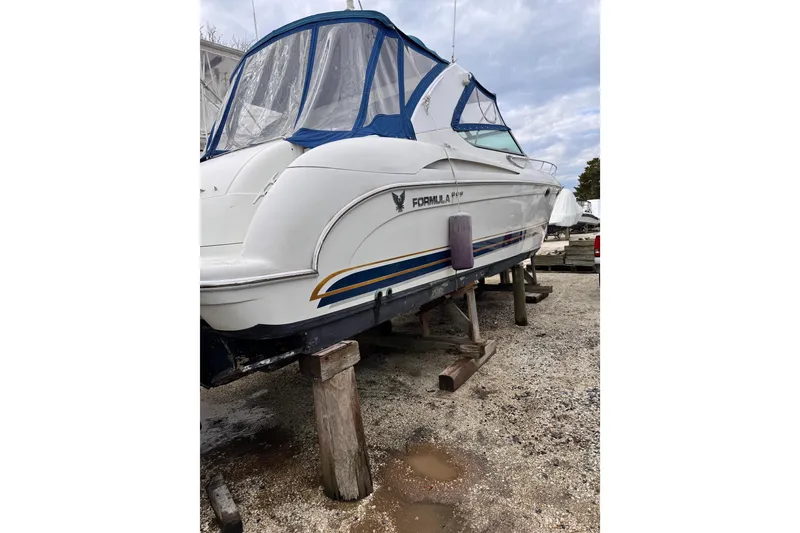 Slide: The Image of 1999 Formula 400 Super Sport boat on stands, blue canopy, outdoor storage. - 54