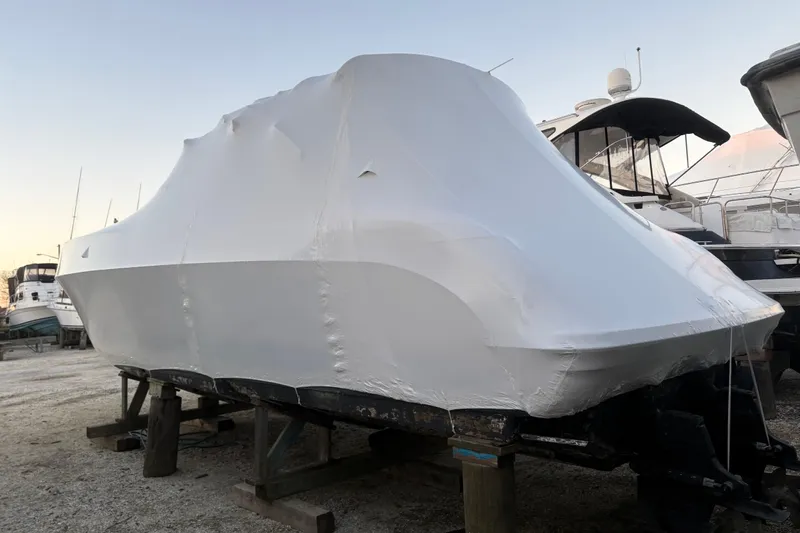 Slide: The Image of 1999 Formula 400 Super Sport boat covered in protective wrap, stored on wooden supports. - 57